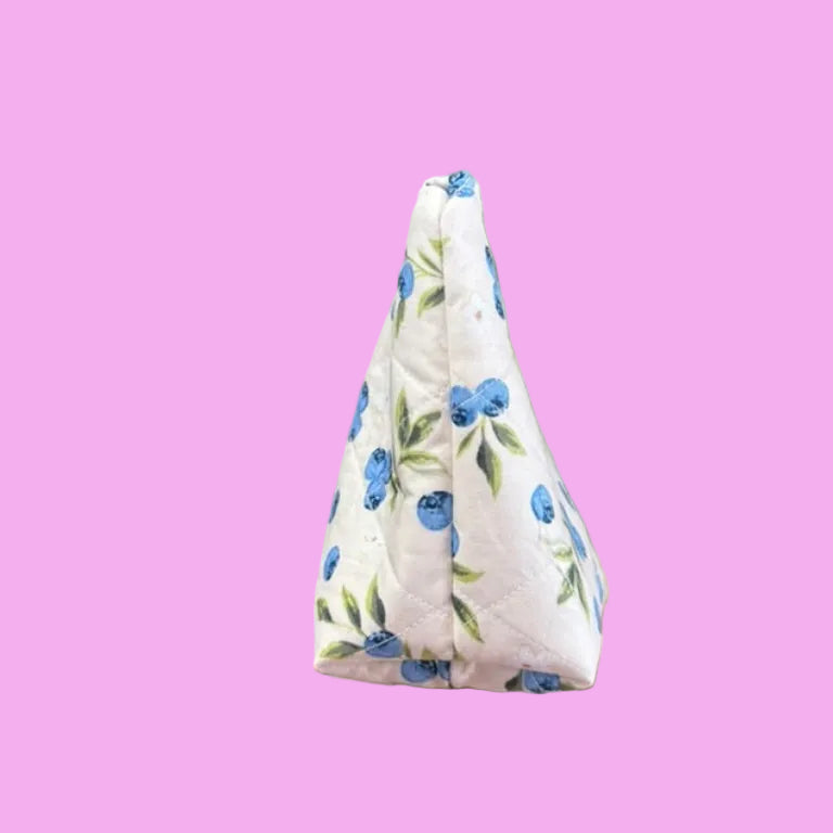 A hand holding a small triangular fabric pouch with a blue floral print.