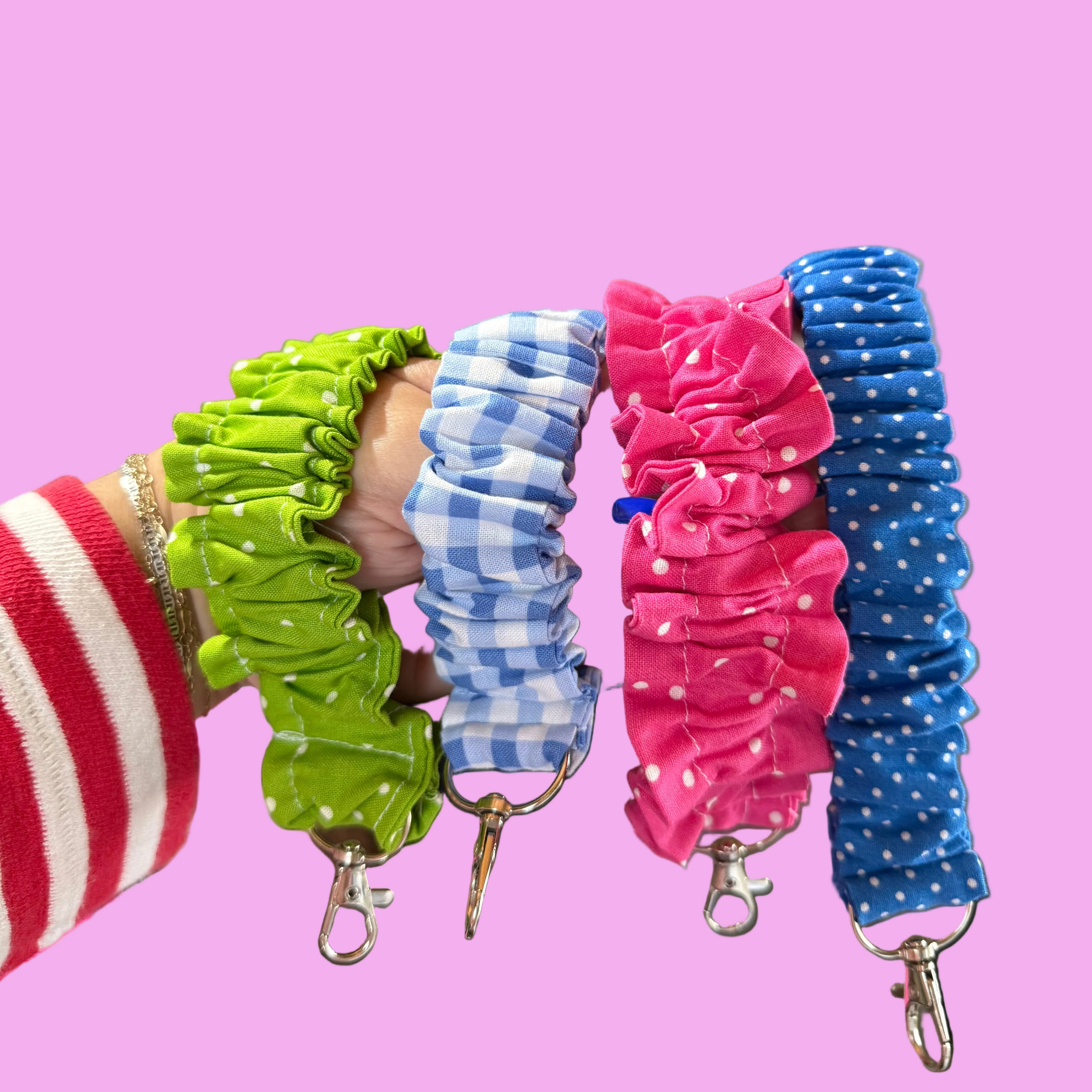 Four fabric scrunchie keychains in green, blue-and-white gingham, pink, and blue polka dot.