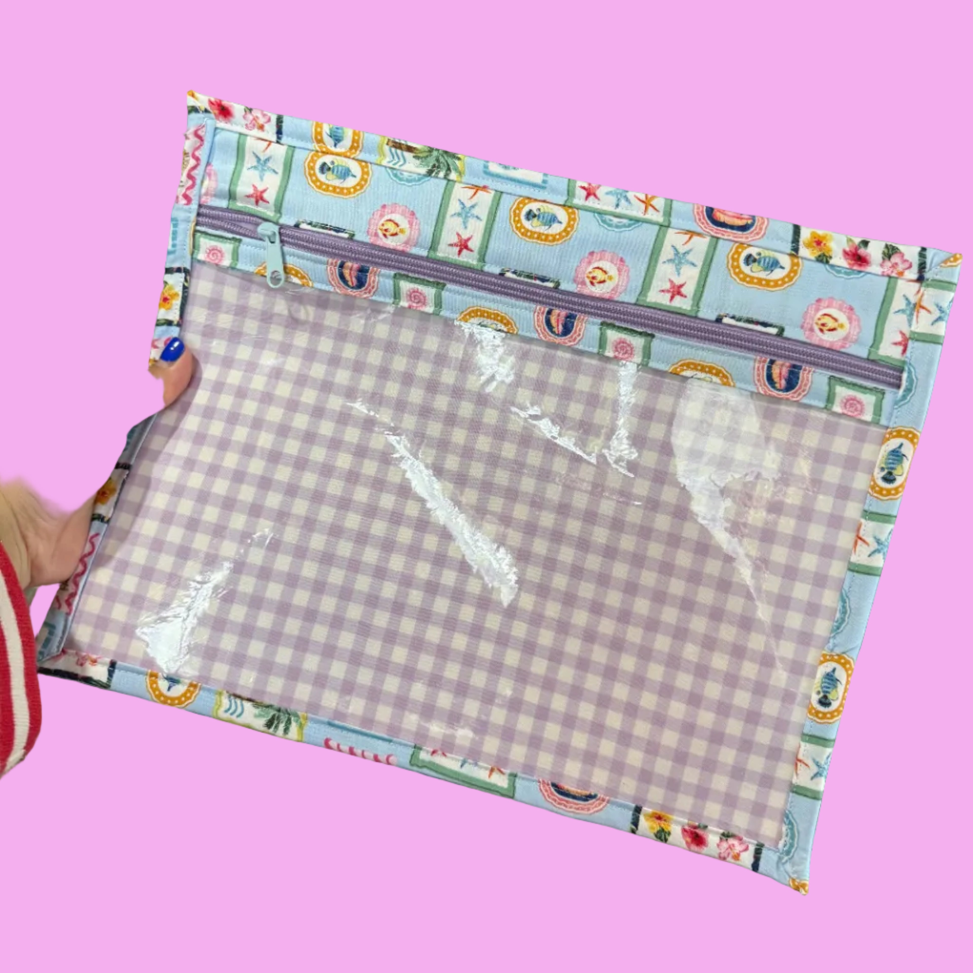 A handmade fabric organizer pouch with a lavender and white gingham patterned center and a colorful patterned border.
