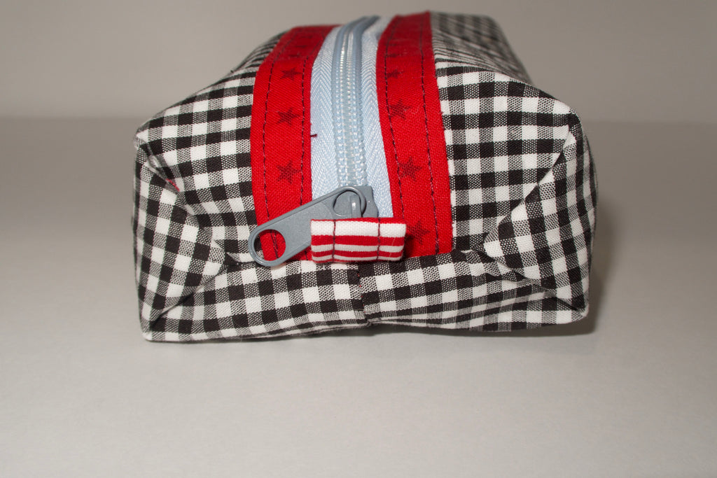 Black and white checkered pouch with red zipper on a gray background