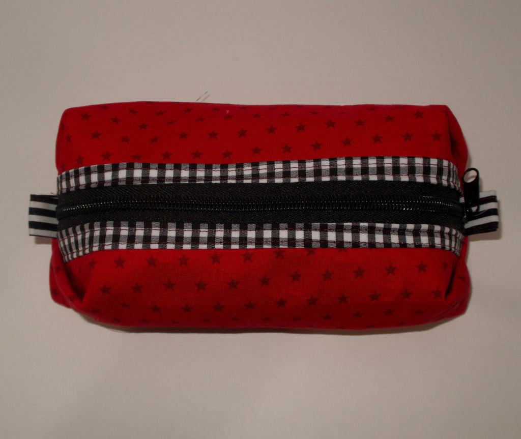 Red fabric pouch with black and white checkered zipper on a beige background