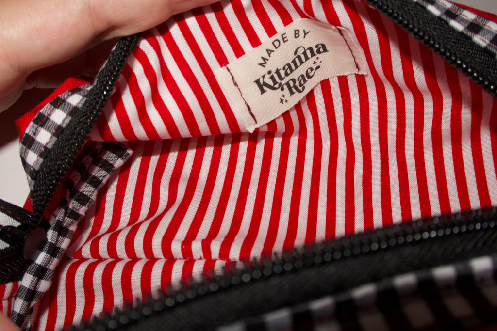 Red and white striped fabric with a visible brand label, held by a hand.