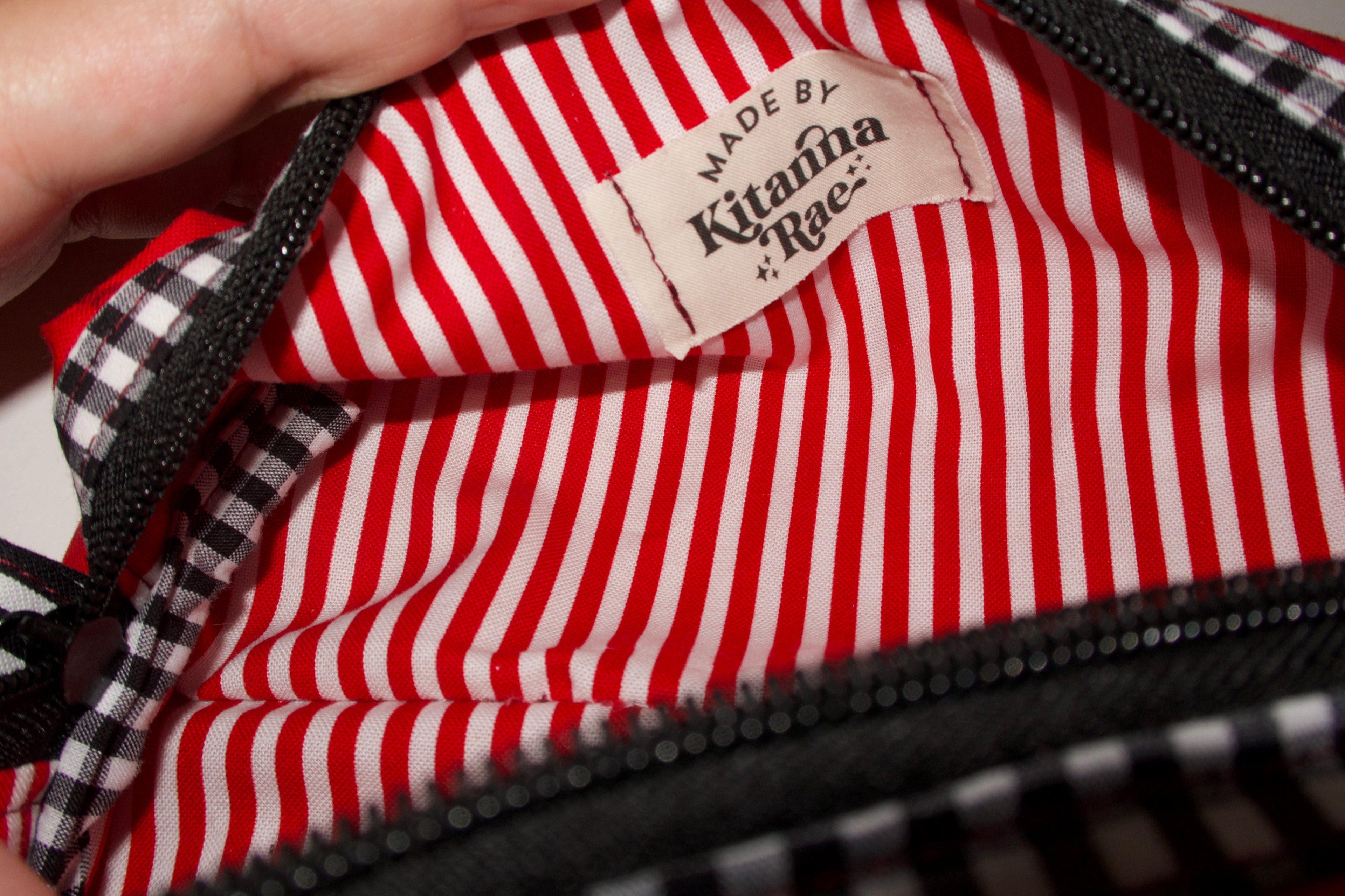 Red and white striped fabric with a visible brand label, held by a hand.