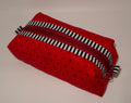 Red fabric pouch with black star pattern and a black and white striped zipper on a beige background