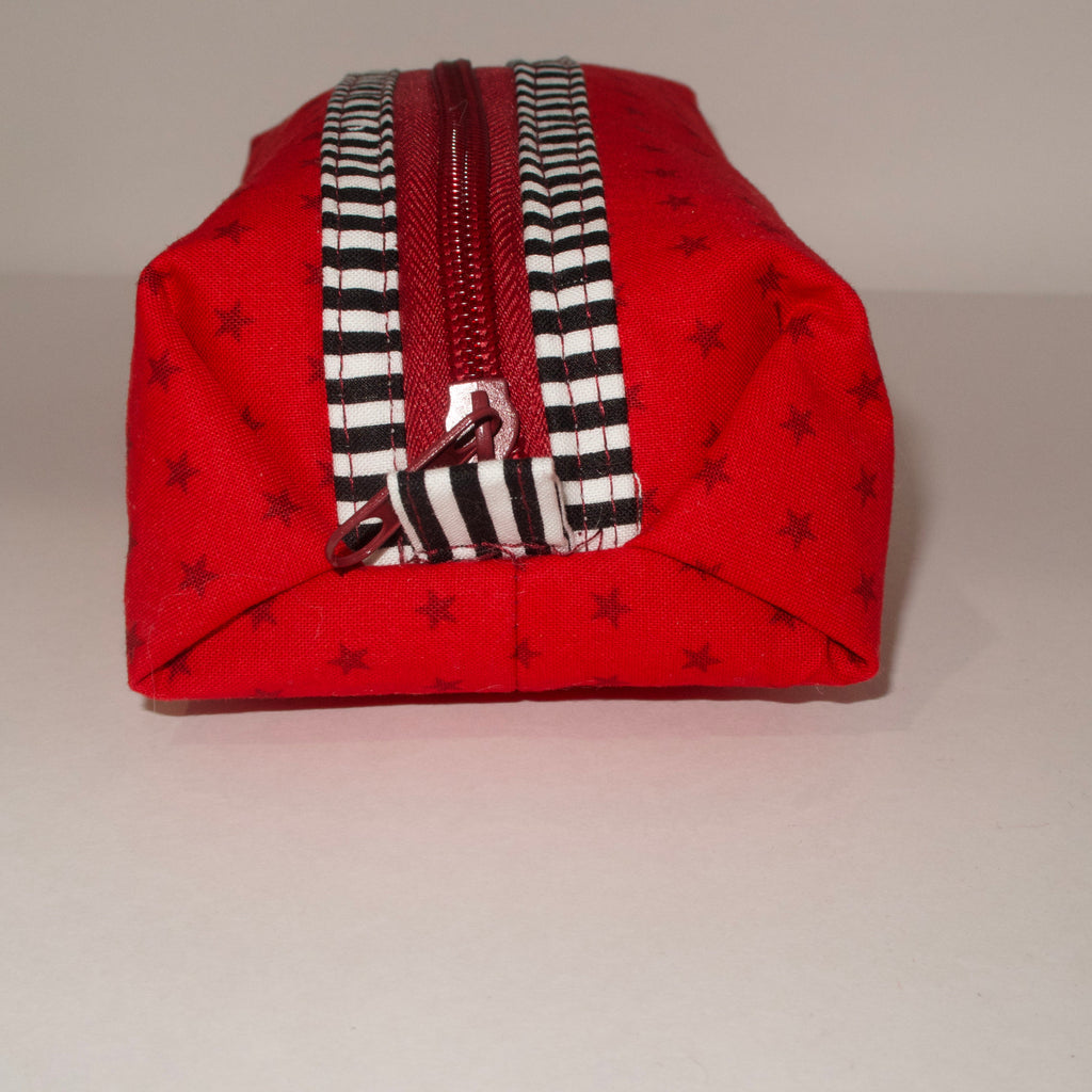 Red fabric pouch with a striped zipper on a light gray background