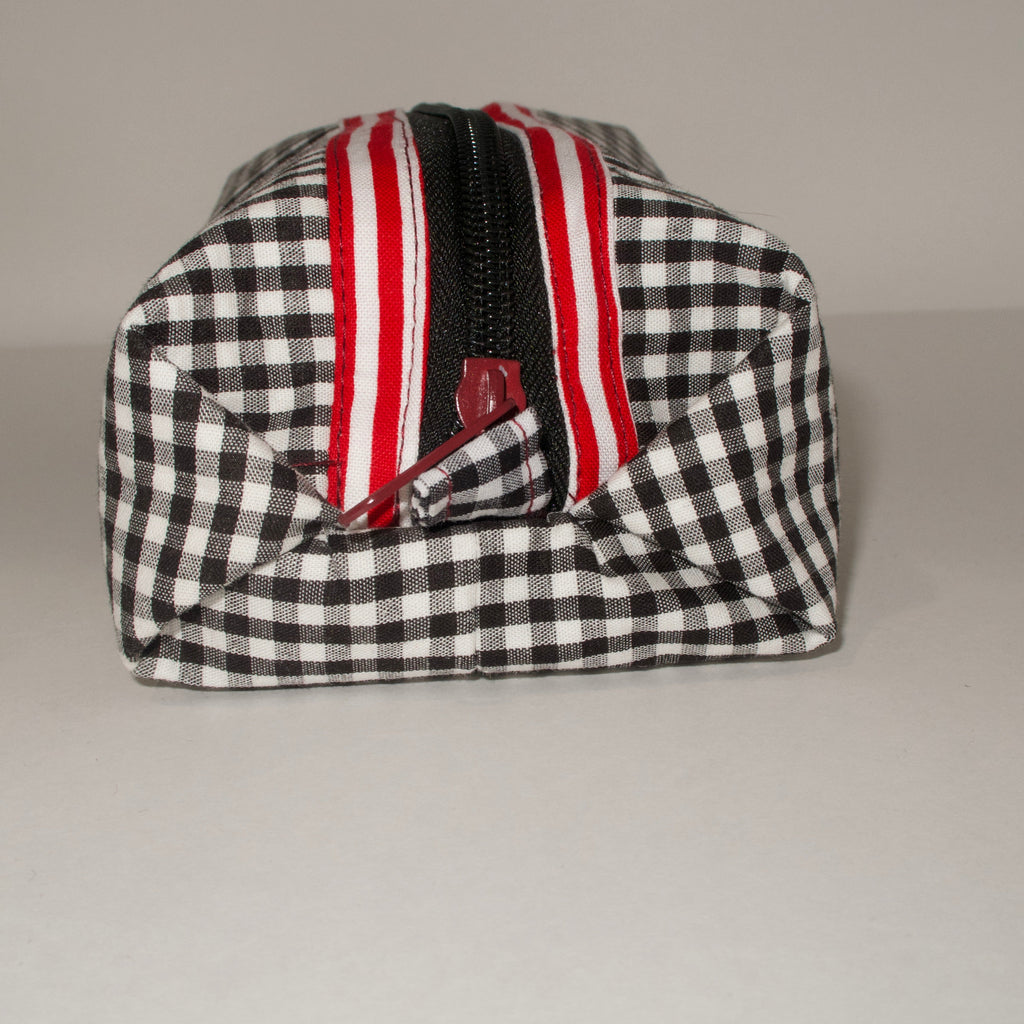 Black and white checkered bag with red and white striped zipper on a gray background