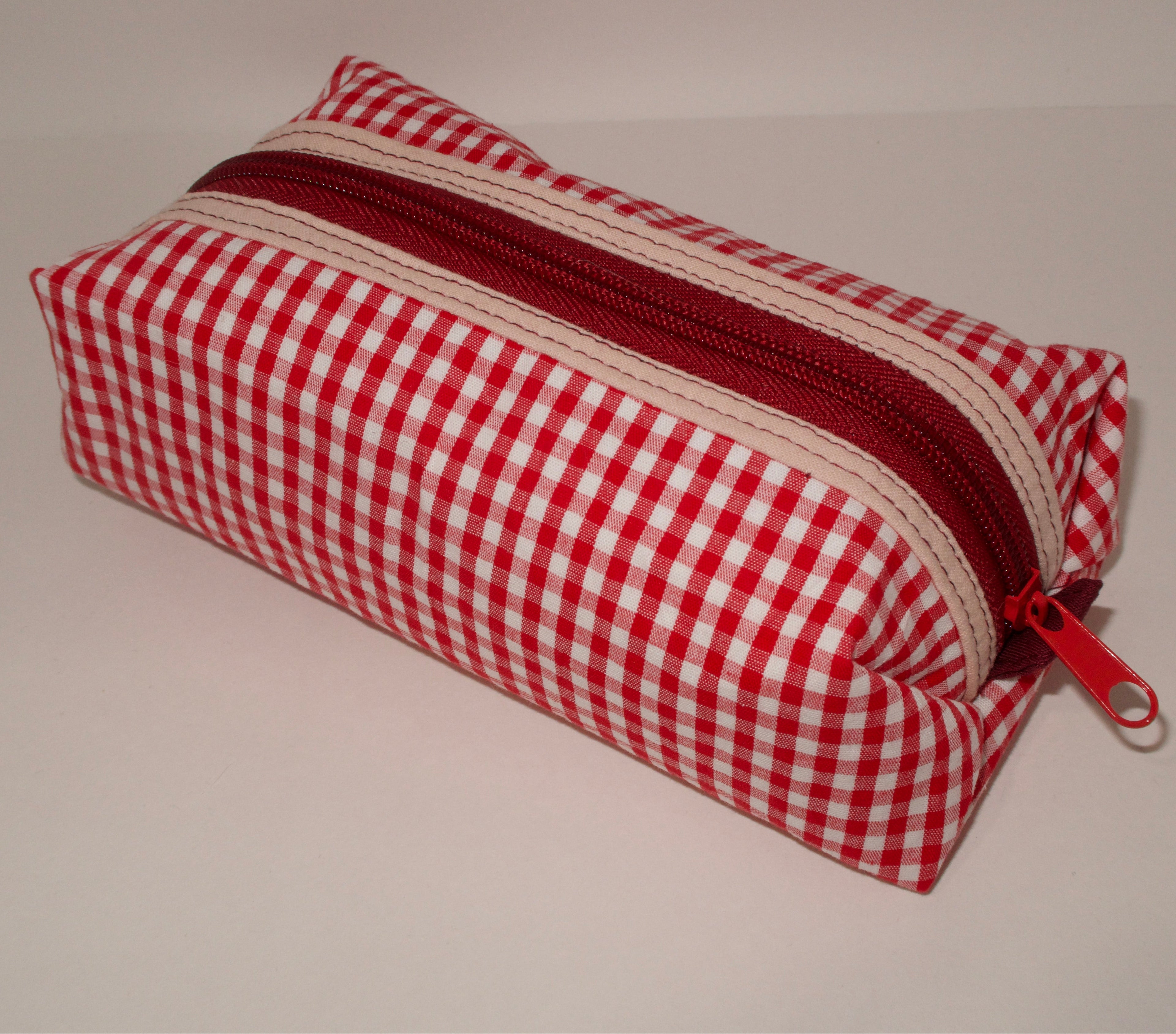 Red and white checkered pencil case with a red zipper on a light gray background