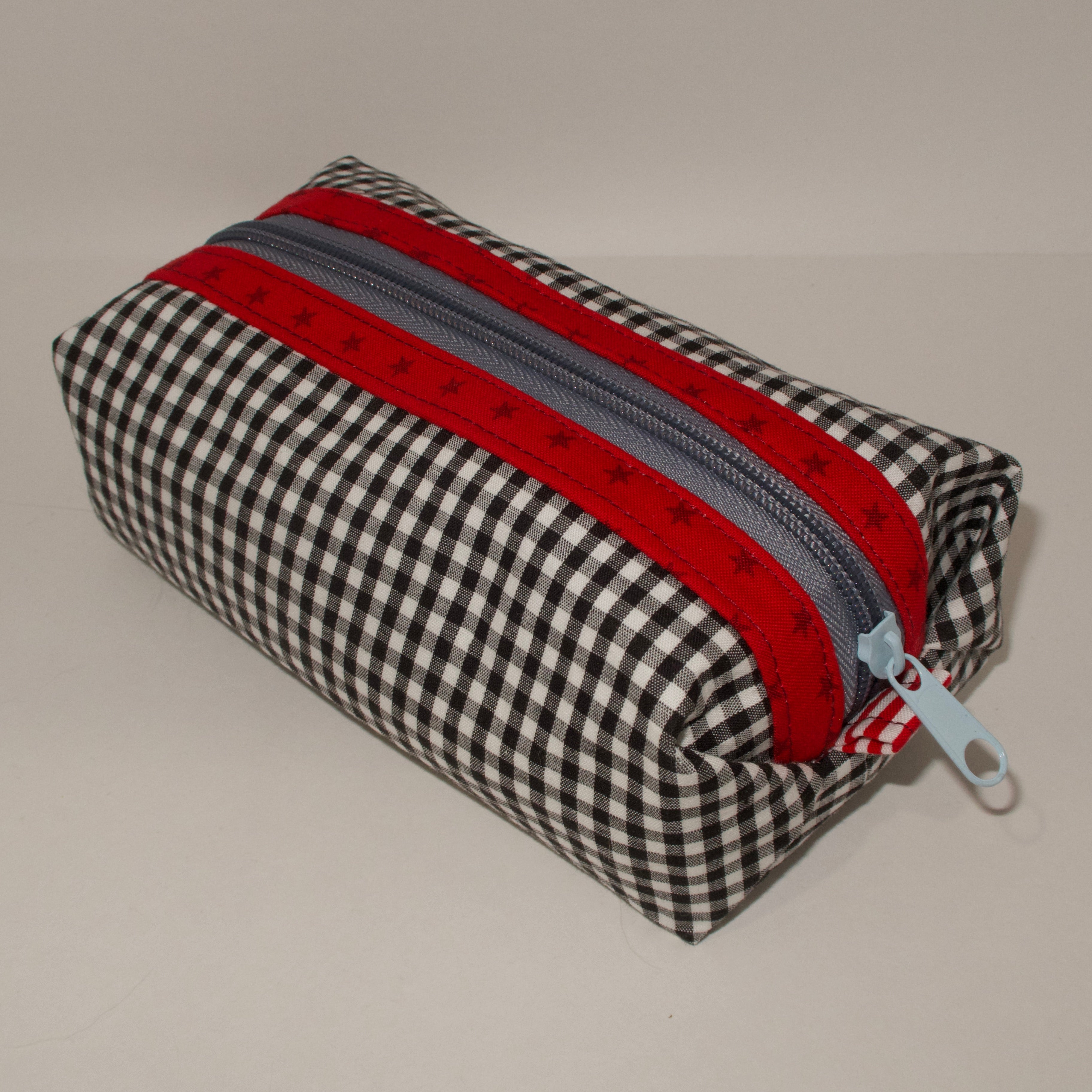 Checkered pouch with red and gray zipper on a beige background
