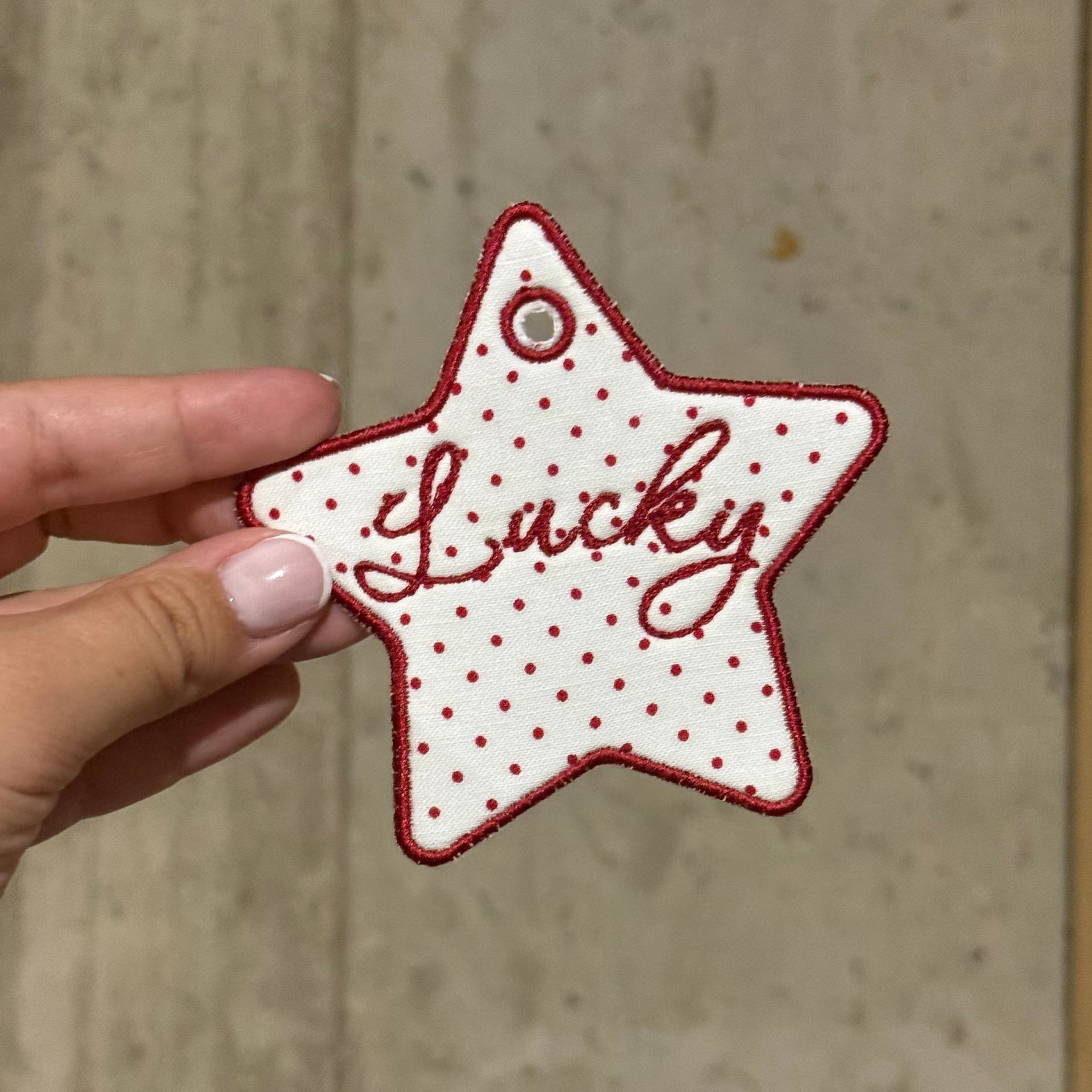 Star-shaped lucky charm held by a hand against a concrete wall.