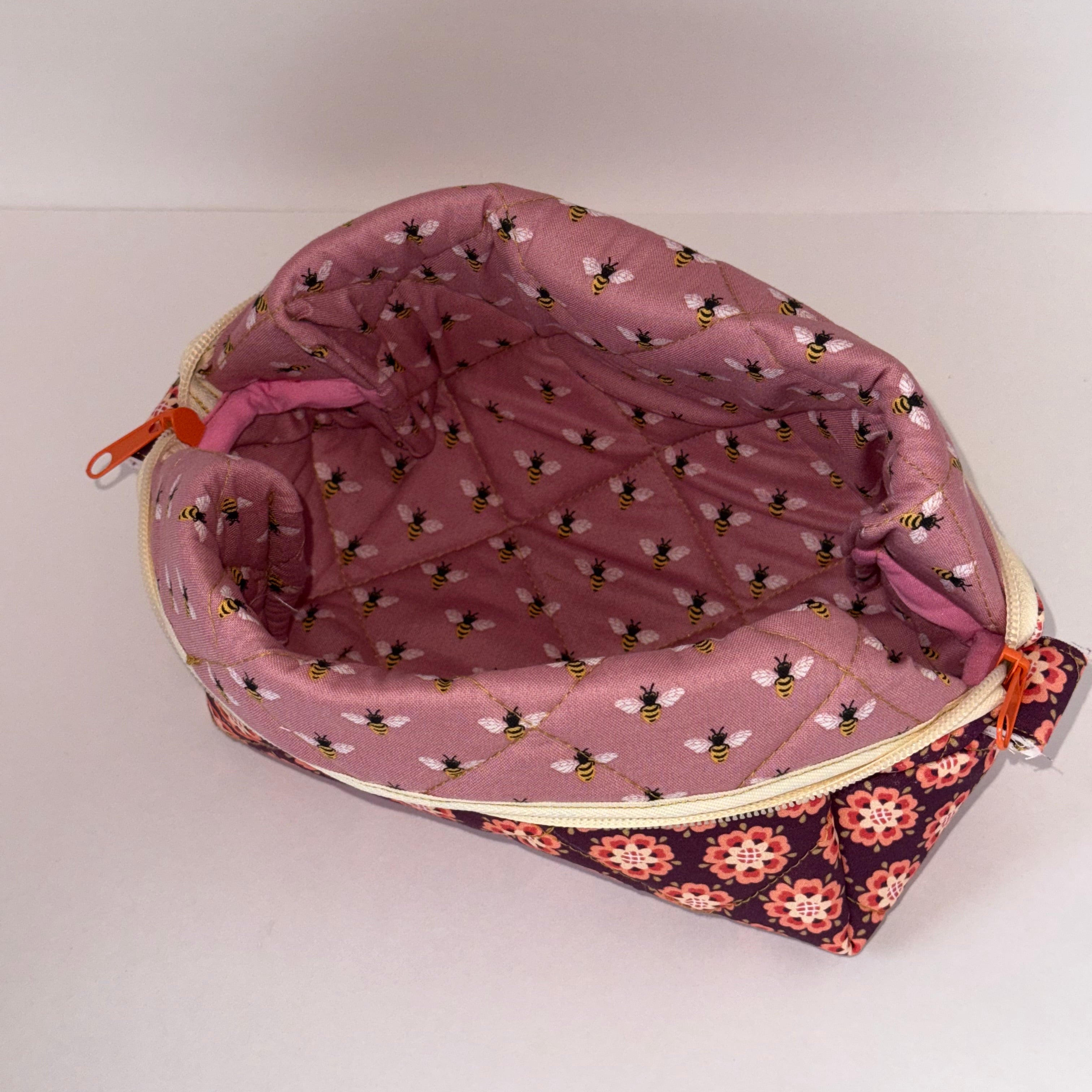 Pink pouch with bee pattern on a white background