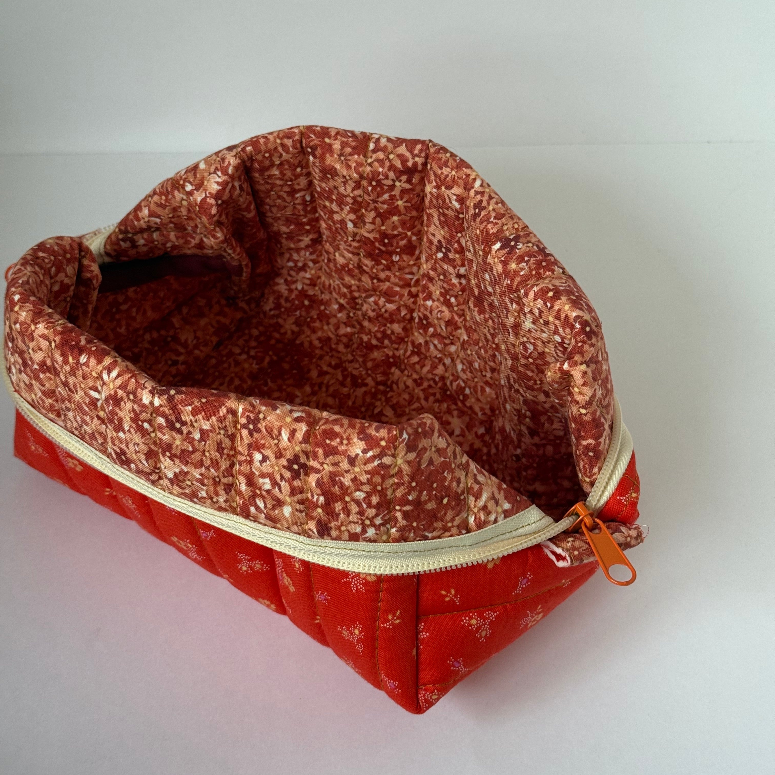 Red patterned pouch with a zipper on a light gray background