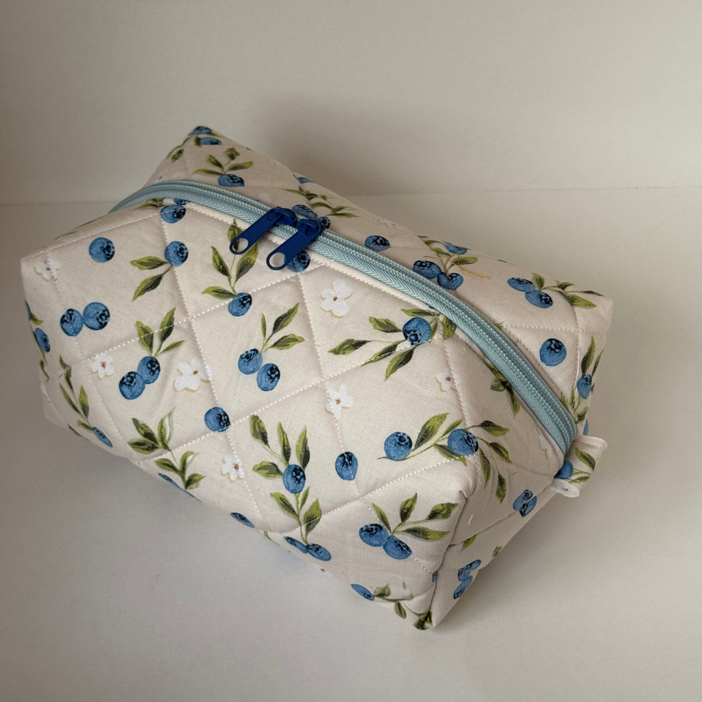 Floral-patterned pouch with a blue zipper on a plain background