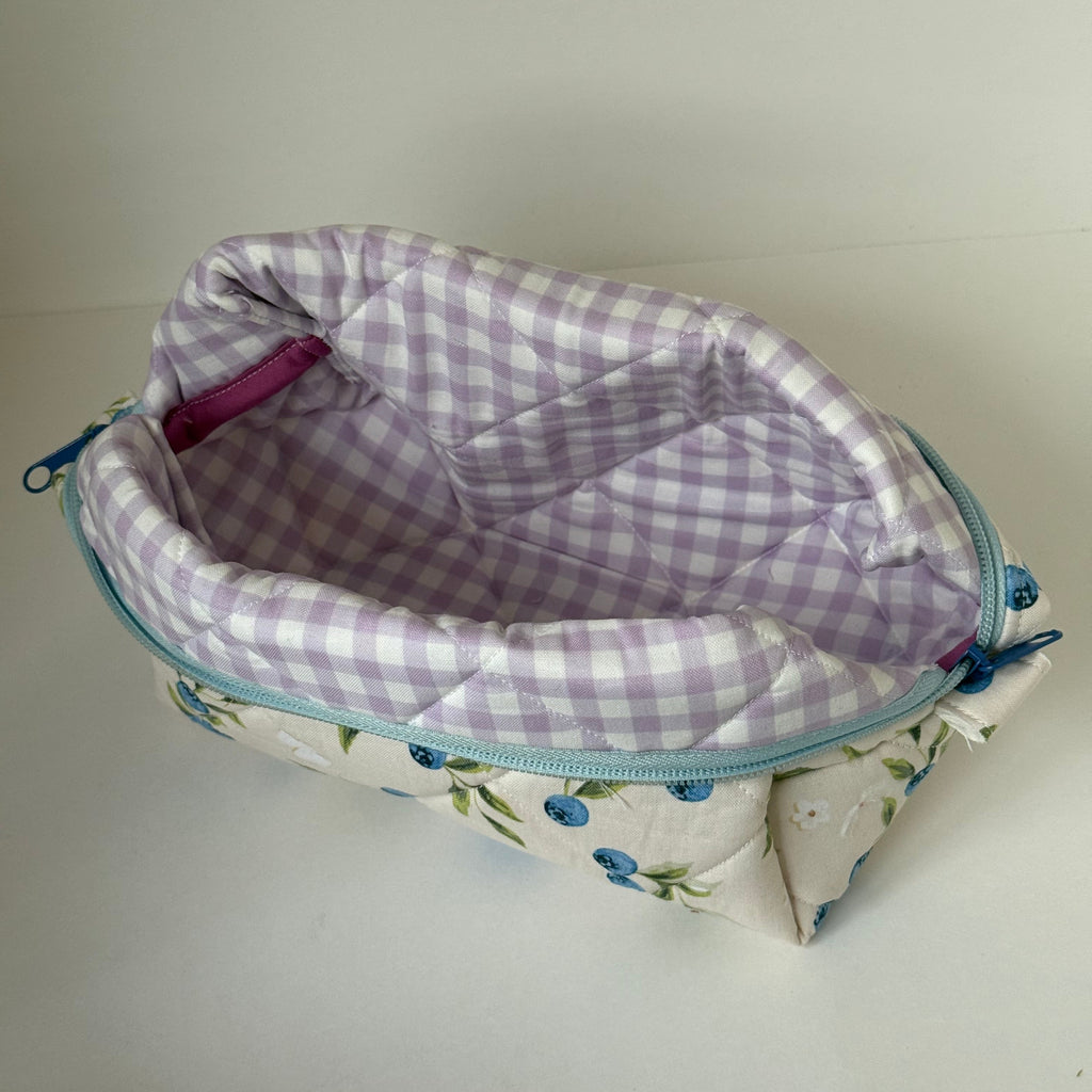 Floral-patterned pouch with a checkered interior on a plain background