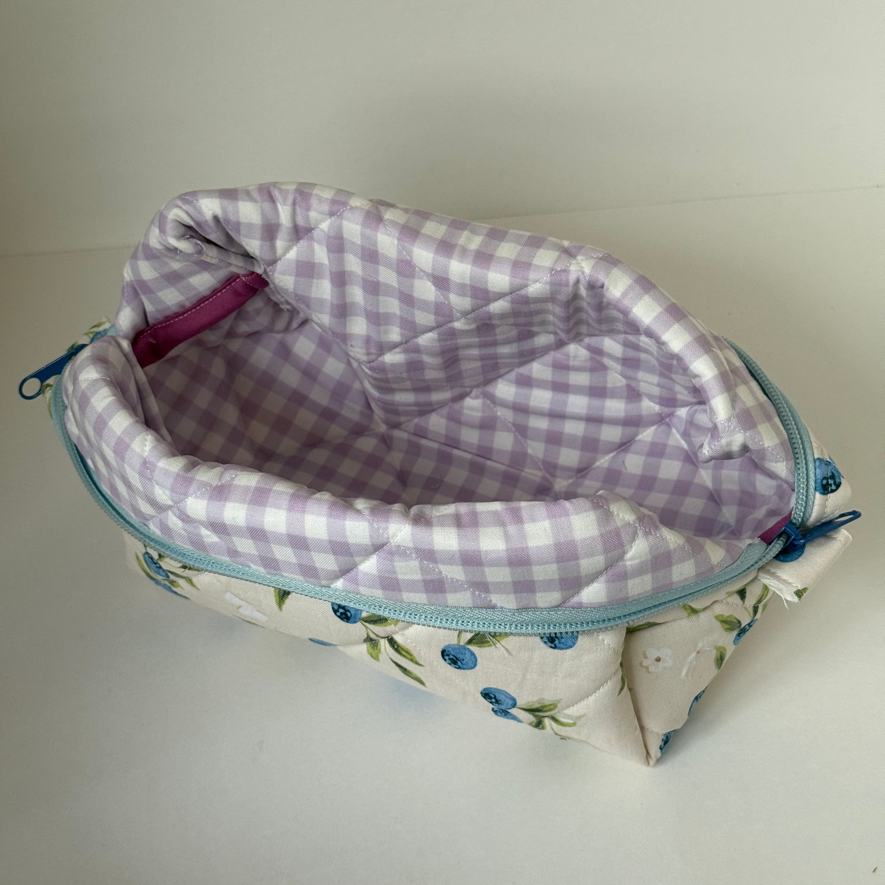 Floral-patterned pouch with a checkered interior on a plain background